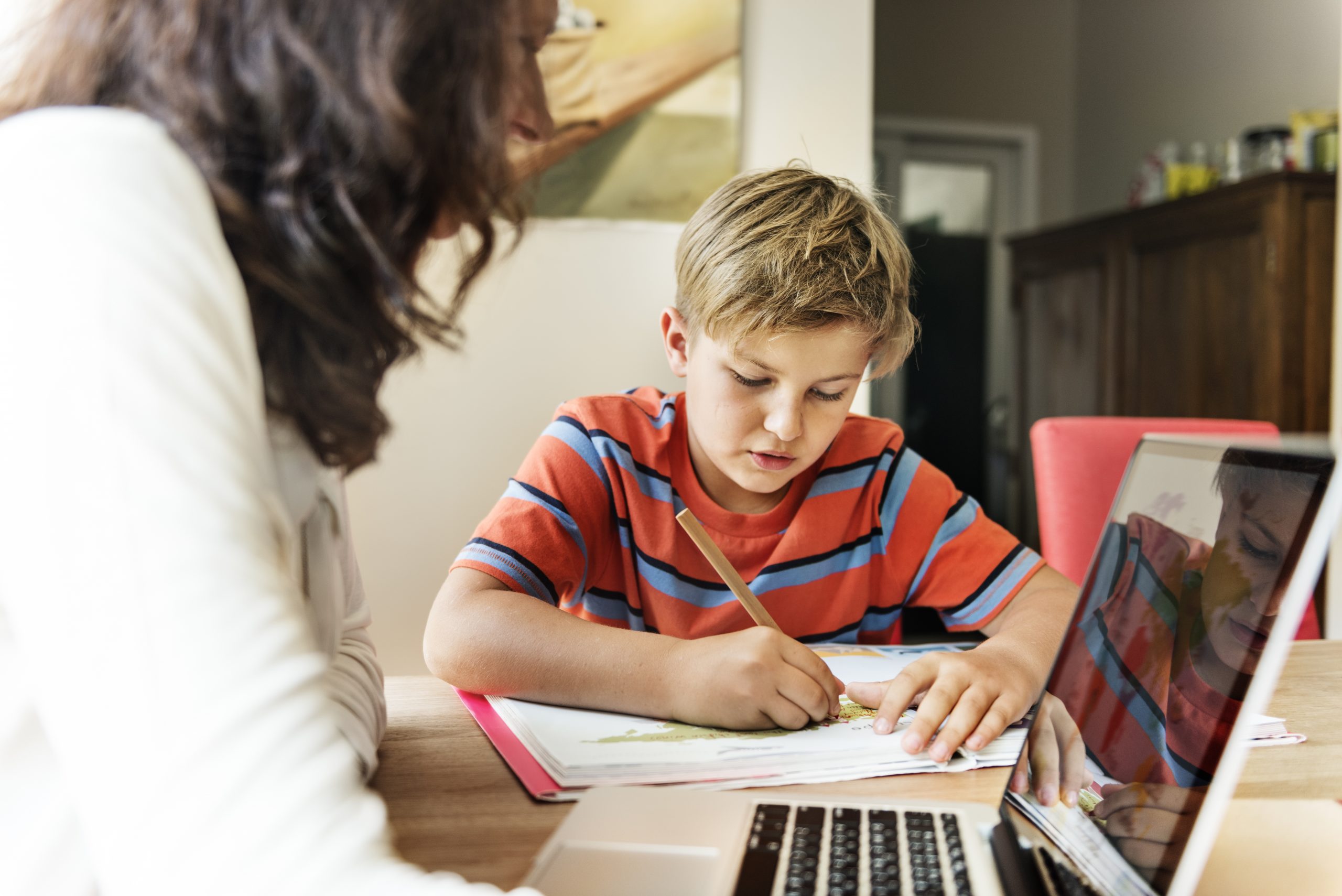 child working on homework with adult overseeing